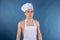 Young chef with apron on naked muscular body on blue background