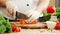 Young chef is cutting carrots in a modern kitchen. The man prepares food at home. Cooking healthy food.