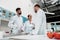 Young chemists in white coats standing and talking in laboratory