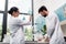 Young chemists in white coats working with flasks and test tubes in chemical lab