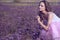 Young chic woman with artistic make up and long flying hair smelling violet flowers with closed eyes