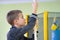 Young child boy exercising on a wall ladder bar inside sports gym room in a school