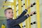 Young child boy exercising on a wall ladder bar inside sports gym room in a school