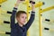 Young child boy exercising on a wall ladder bar inside sports gym room in a school