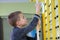 Young child boy exercising on a wall ladder bar inside sports gym room in a school