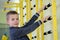 Young child boy exercising on a wall ladder bar inside sports gym room in a school