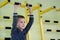 Young child boy exercising on a wall ladder bar inside sports gym room in a school