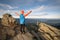 Young child boy hiker standing with raised hands in mountains enjoying view of amazing mountain landscape at sunset