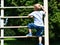 The young child climbs up the stairs. Cute baby boy plays on the stairs. The concept of happy childhood. Nature, outdoors, summer.