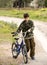 Young child dressed in army clothes with a bicycle on a walk in