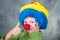 Young child dressed as a clown with wig and fake nose smiling and thumbs up