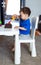 Young child engrossed in play at a table with a toy. A little boy sitting at a table playing with a toy