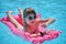 Young child girl falling in water from inflatable air mattress in swimming pool while swinnimg during tropical vacations