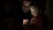 Young child girl with father playing game on mobile phone in dark room,