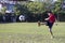 Young child kick soccer ball in green grass field