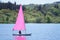 Young child learning to sail on pink yacht on lake for recreation