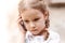 Young child, little school age girl talking on the phone, holding her modern smartphone next to her ear, portrait, face closeup