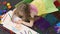 Young child lying on floor and drawing cute picture in illustration school