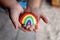 Young Child`s LIttle Hands Holding Painted Rainbow Rock