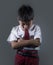 Young child in school uniform feeling sad and depressed looking down scared and embarrassed victim of bullying and abuse