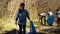 Young child using tongs tool to grab and pick up trash from the woods