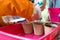 Young children learning how to plant seeds in garden. Narrow depth of field of hands holding seeds and black soil in pot.