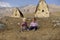 Young children sit in the dry grass on the background of mountains and ancient Ossetian buildings.