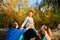 Young children sit next to a pregnant woman and hold their hands on their mother`s belly in the forest in nature