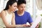 Young Chinese Couple Sitting Using Laptop At Home