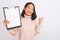 Young chinese inspector woman holding clipboard standing over isolated white background happy with big smile doing ok sign, thumb