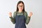 Young chinese shopkeeper woman wearing apron and glasses over isolated white background celebrating surprised and amazed for