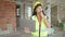 Young chinese woman architect talking on walkie-talkie using laptop at construction site