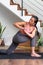 Young Chinese woman doing low lunge twist yoga pose at home. Parivrtta anjaneyasana home yoga practice. Vertical image.