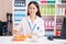 Young chinese woman pharmacist smiling confident organizing pills dose at pharmacy