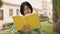 Young chinese woman reading book with relaxed expression at park