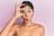 Young chinese woman standing topless showing skin doing ok gesture shocked with surprised face, eye looking through fingers