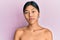 Young chinese woman standing topless showing skin relaxed with serious expression on face