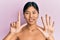 Young chinese woman standing topless showing skin showing and pointing up with fingers number seven while smiling confident and