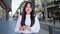 Young chinese woman using smartphone smiling at street