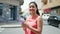 Young chinese woman using smartphone smiling at street