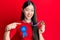 Young chinese woman wearing first place badge holding medal pointing finger to one self smiling happy and proud