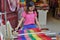 Young Chinese woman working on a loom weaving a red scarf