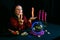 Young clairvoyant and fortune teller with candles in hands in a magic salon on a black background