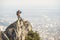 A young climber looking out of the top of a steep cliff against the background of caucasian city and mountains