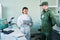 Young clinician in coveralls making report to military man in camouflage uniform