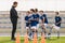 Young coach explaining training rules to children school soccer team