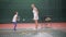 A young coach teaches a little girl to play tennis, a child tries to hit a tennis ball with a racket, a woman throws the