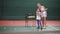 The young coach teaches to keep the child`s racket correctly, the girl actively waves her hand to learn how to beat off