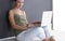 A young colledge girl sitting on the floor with a laptop