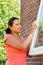 Young colombian woman sanding window outdoors